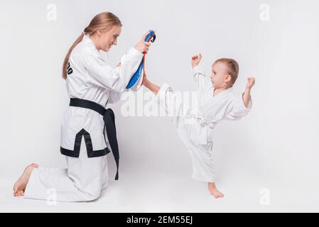 Madre suo figlio piccolo che pratica arti marziali su sfondo bianco. Foto Stock