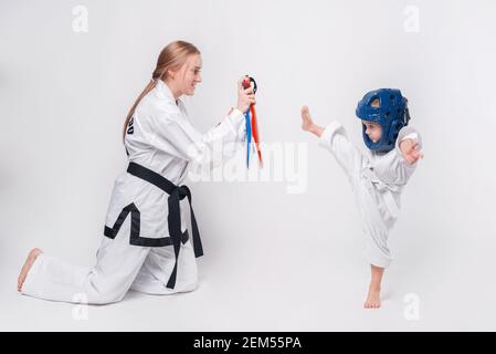 Madre suo figlio piccolo che pratica arti marziali su sfondo bianco. Foto Stock