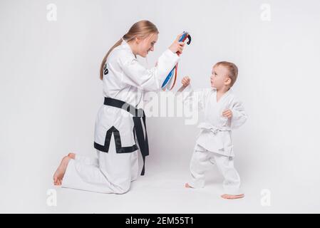 Madre suo figlio piccolo che pratica arti marziali su sfondo bianco. Foto Stock