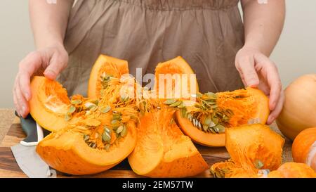 Donna taglia la zucca arancione in fette su tagliere di legno. Step by step purea di zucca ricetta, stile di vita Foto Stock