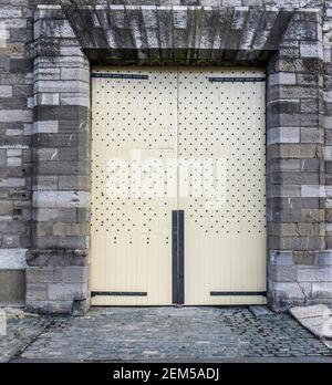 Una vecchia porta in legno restaurata con borchie, circondata da mattoni, su un edificio dell'Università tecnologica di Dublino, Grangegorman, Dublino, Irlanda. Foto Stock