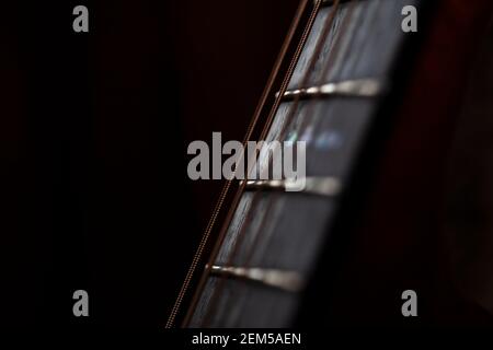 Primo piano di una chitarra strung in acciaio rosewood fretboard o fingerboard.Shot contro uno sfondo scuro.le corde sono il tipo bronzo fosforoso. Foto Stock