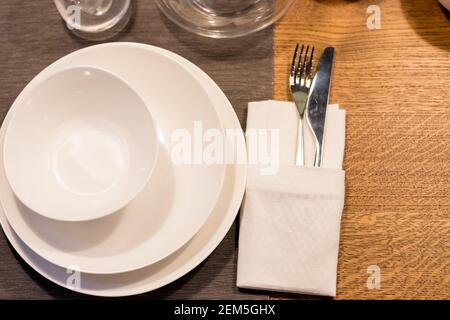 Tavolo con piatti e bicchieri prima di una festa. Pile di stoviglie in ceramica bianca, piatti, piattini, tazze su un tavolo di legno. stoviglie.tavolo festivo Foto Stock