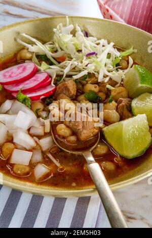 Porco messicano Pozole rojo e stufato di casalinga con varietà di guarnizioni di verdure fresche da guarnire Foto Stock