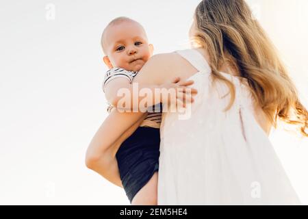 Felice famiglia all'aperto, madre lancia il bambino, ride e gioca in estate sulla natura Foto Stock