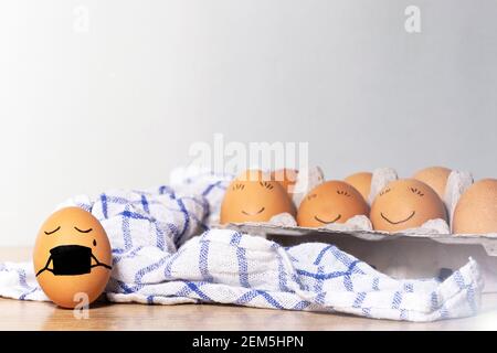 Uova di Pasqua creative con protezione del virus di Corona, uovo in una maschera nera in una quarantena. Uova di pollo diverse con sorriso su sfondo grigio. Disposizione piatta Foto Stock