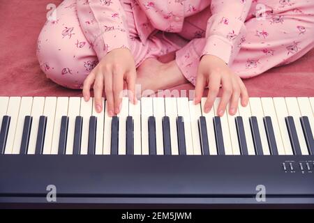 Donna in pigiama imparando a suonare il piano seduto a letto, le mani si avvicinano Foto Stock