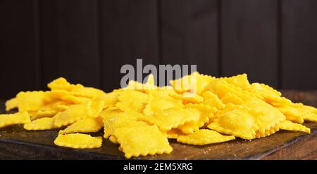 Ravioli piccoli con formaggio o carne da cuocere in brodo, piatto tradizionale per celebrazioni in italia, regione Emilia Romagna. Pasta fresca fatta in casa con ripieno su un tavolo di legno. Spazio di copia Foto Stock