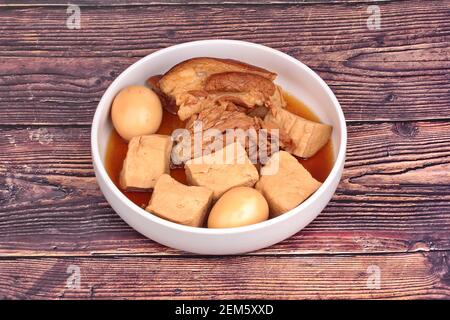 Uovo bollito stufato con tofu e carne di maiale streaky in zuppa cinese marrone. Foto Stock