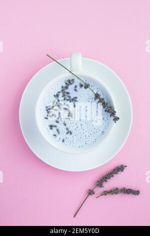 Vista dall'alto del latte lunare di lavanda nella tazza bianca sulla superficie rosa. Posizione verticale. Foto Stock
