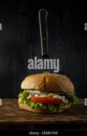 burger con lattuga, pomodoro e maionese servito su un rustico tavolo di legno, con copyspace Foto Stock