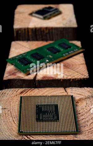 Processore e memoria RAM da un personal computer impilati su legno grezzo. Accessori e pezzi di ricambio per la riparazione del computer. Sfondo scuro. Foto Stock