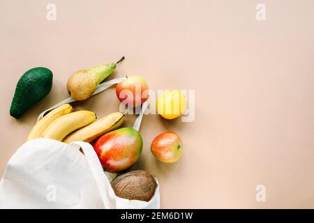 Frutta in un sacchetto di stoffa, banane, mele, limone, pera, mango, avocado e cocco. Vista dall'alto, disposizione piatta, spazio per la copia. Concetto di cibo sano senza sprechi. Foto Stock