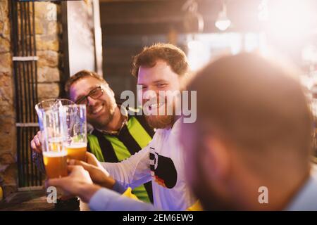 Gli appassionati di calcio si salutano con le pinte di birra nel loro pub preferito. Foto Stock