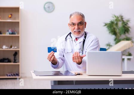 Vecchio medico che detiene la carta di credito Foto Stock