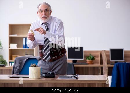 Anziano dipendente che soffre di radicolite sul posto di lavoro Foto Stock