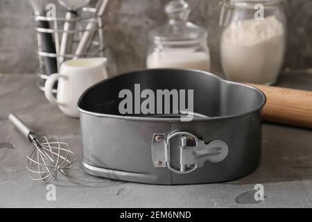 Forma da forno per torte, utensili da cucina e ingredienti su sfondo scuro Foto Stock