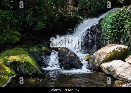 Una grande corrente d'acqua che scorre intorno a formazioni rocciose dalla cascata di Ipiranguinha formando una piscina naturale proprio sotto nella fitta foresta di Serra do Mar. Foto Stock