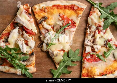 Fette di pizza gustosa su sfondo di legno Foto Stock