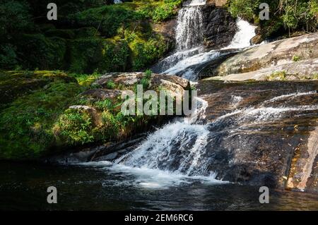 Particolare della corrente d'acqua che scorre sulle formazioni rocciose della cascata Ipiranguinha formando una piscina naturale proprio sotto nel parco della tenuta Serra do Mar. Foto Stock