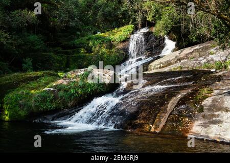 Corrente d'acqua che scorre intorno a formazioni rocciose della bella cascata Ipiranguinha formando una piscina naturale proprio sotto nella foresta di Serra do Mar. Foto Stock