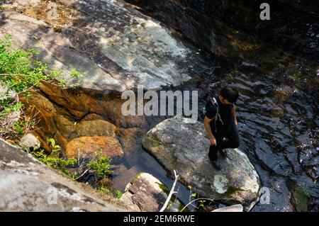 CUNHA, SAO PAULO, BRASILE - 18 AGOSTO 2019: Uno zaino in spalla che attraversa la piscina naturale cristallina formata dalla cascata Ipiranguinha nel mezzo di Serra Foto Stock