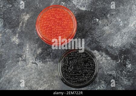 Lastre di vetro piene di caviale rosso e nero su a. sfondo in marmo Foto Stock