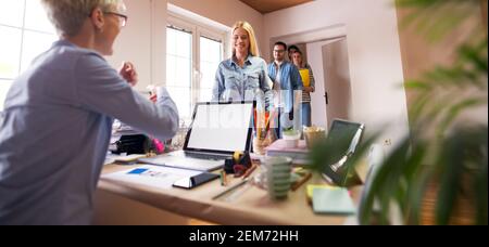 Gruppo di giovani ingegneri felici è stato informato che hanno ottenuto il lavoro quando entrano nell'ufficio del loro nuovo capo. Foto Stock