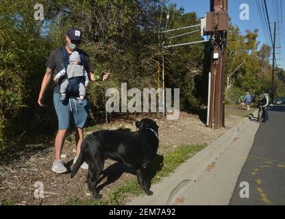 Rolling Hills Estates, Stati Uniti. 24 Feb 2021. Il residente locale Enrique Santana porta il suo figlio di sei mesi Alister in una passeggiata vicino alla zona dove la leggenda del golf Tiger Woods ha rotolato la sua auto dopo aver attraversato una mediana a Rolling Hills Estates, California, mercoledì 24 febbraio 2021. Gli esperti dicono che Tiger Woods ha una lunga strada per andare nel suo processo di recupero dalle ferite rotte della gamba, della caviglia e del piede ha sostenuto in un incidente di auto Martedì nella California del Sud. Foto di Jim Ruymen/UPI Credit: UPI/Alamy Live News Foto Stock