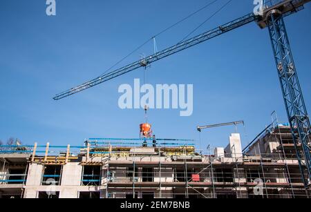 Amburgo, Germania. 24 Feb 2021. Una gru da costruzione si trova su un cantiere di costruzione alla nuova costruzione di un edificio di appartamenti, sul quale è installato un ponteggio. Il 25.02.2020 la BFW Landesverband Nord informa sullo stato attuale delle attività di costruzione residenziale nella Germania settentrionale. Credit: Daniel Bockwoldt/dpa/Alamy Live News Foto Stock