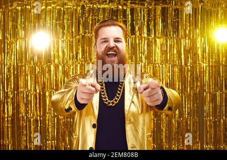 Divertente uomo grasso in costume d'oro che punta alla macchina fotografica e. sensazione di allegria Foto Stock