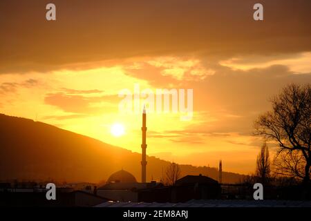 Bursa durante il tramonto con magnifiche nuvole e riflesso del sole sul cielo. Tramonto, uludag, moschea, minareto con pino. Tutte le silhouette in sundown Foto Stock