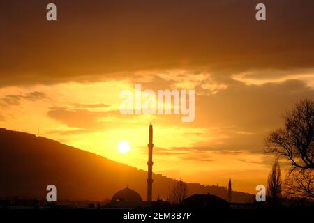 Bursa durante il tramonto con magnifiche nuvole e riflesso del sole sul cielo. Tramonto, uludag, moschea, minareto con pino. Tutte le silhouette in sundown Foto Stock