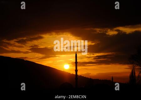 Bursa durante il tramonto con magnifiche nuvole e riflesso del sole sul cielo. Tramonto, uludag, moschea, minareto con pino. Tutte le silhouette in sundown Foto Stock