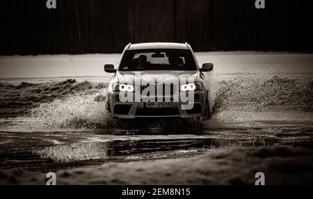 Riga, Lettonia 10 febbraio 2021 - bmw corre sull'acqua, spray dalla macchina. Vista frontale. Foto Stock