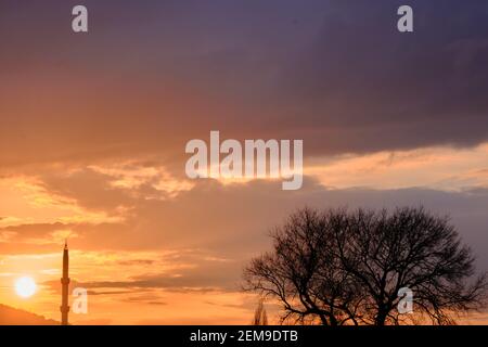 Bursa durante il tramonto con magnifiche nuvole e il sole riflesso sul cielo. Tramonto, uludag (enorme montagna a Bursa), moschea e il suo minareto Foto Stock