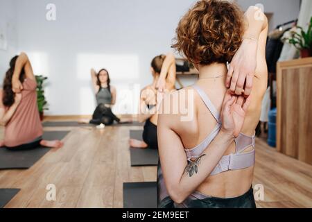 Primo piano immagine della donna che pratica yoga in un gruppo, collegando le dita Foto Stock