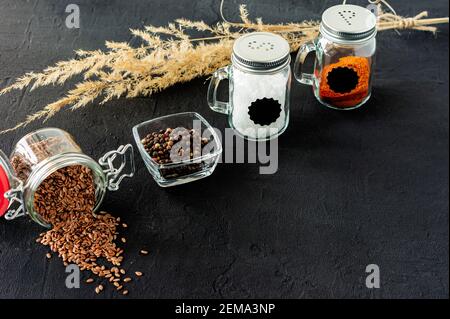 agitatori in vetro sale e pepe su un fondo nero in cemento con spazio per la copia. Foto Stock