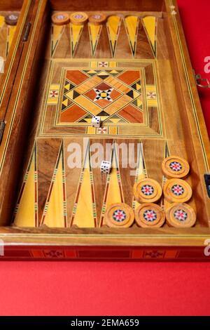 Un divertente gioco di backgammon su sfondo rosso. Dama, cubetti, tavola fatta a mano Foto Stock