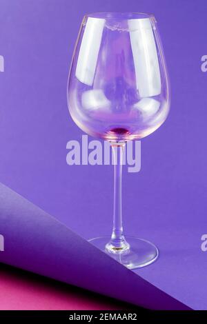 Svuotare il bicchiere di vino sporco su sfondo blu e rosa. Bicchiere di vino rosso a stelo alto. Messa a fuoco selettiva. Foto Stock