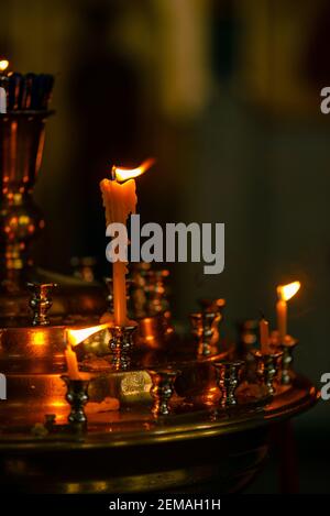 La preghiera della Chiesa candele di cera che bruciano in un russo scarsamente illuminato chiesa Foto Stock