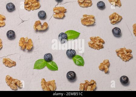 Mirtilli freschi e noci sgusciate su sfondo grigio. Concetto di prodotti naturali. Foto di alta qualità Foto Stock