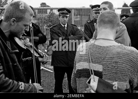 I giocatori fiddle hanno guardato dagli ufficiali della polizia metropolitana ad una protesta contro le strade a Wanstead, Londra Est, come parte della campagna No M11 link Road di azione diretta contro la costruzione della strada M11 link Road nel 1994 Foto Stock