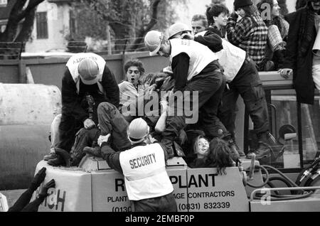 Le guardie di sicurezza tentano di rimuovere i manifestanti stradali che occupano digger sul sito della M11 link Road nella zona est di Londra. Le macchine sono state occupate nel tentativo di fermare la costruzione di strade. Le proteste sono durate 2 anni e hanno finito per raddoppiare quasi il costo del piano stradale. Foto Stock