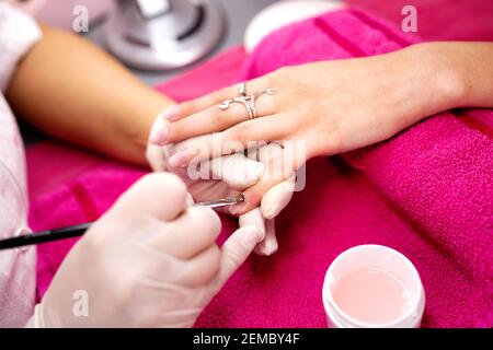 Applicazione di gel base sulla superficie della piastra per unghie, manicure per donne, salone per unghie Foto Stock