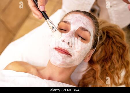 Spalmatura della maschera di bellezza facciale con spazzola cosmetica Foto Stock