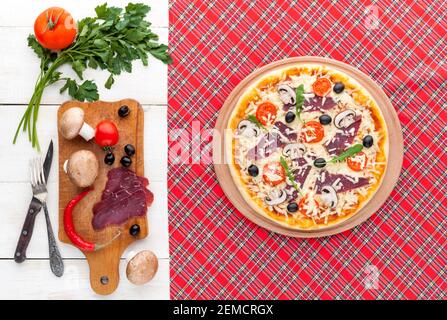 Pizza fresca in stile rustico italiano con olive a scatto funghi e tre tipi di formaggio su un legno chiaro sfondo Foto Stock