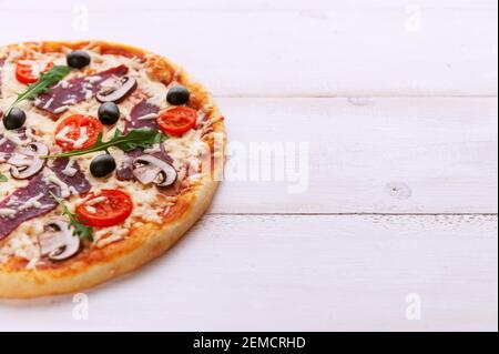 Pizza fresca in stile rustico italiano con olive a scatto funghi e tre tipi di formaggio su un legno chiaro sfondo Foto Stock