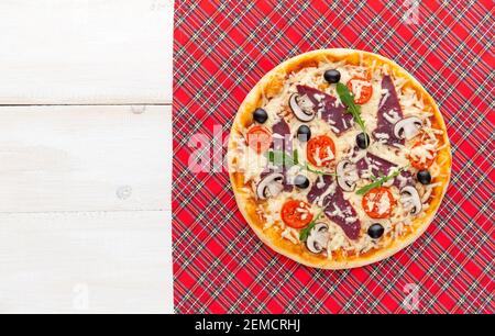 Pizza fresca in stile rustico italiano con olive a scatto funghi e tre tipi di formaggio su un legno chiaro sfondo Foto Stock