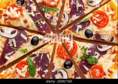 Pizza fresca in stile rustico italiano con olive a scatto funghi e tre tipi di formaggio su un legno chiaro sfondo Foto Stock